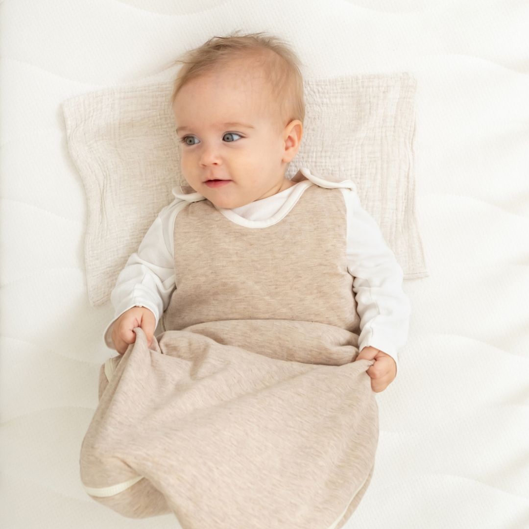 Baby nachts anziehen: Baby liegt im Schlafsack im Babybett.