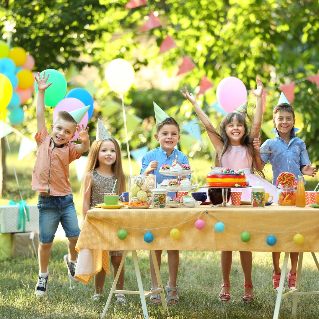 Kindergeburtstag Ideen für 9 bis 10 Jahre: Kinder draußen an Geburtstagstisch.
