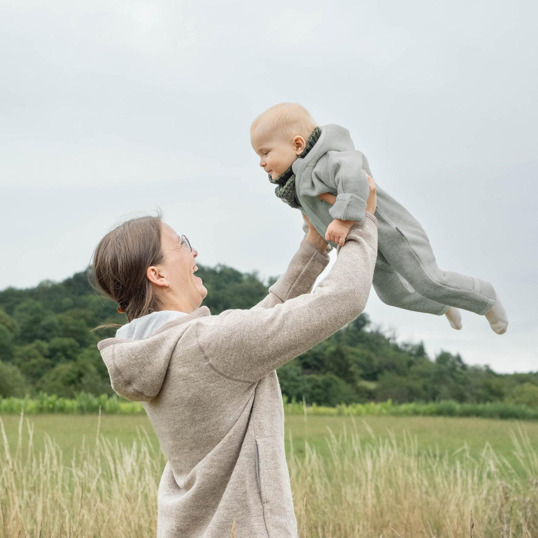 Welche Stoffe fuer Babys_Titelbild Mama hebt Baby im Walkoverall hoch