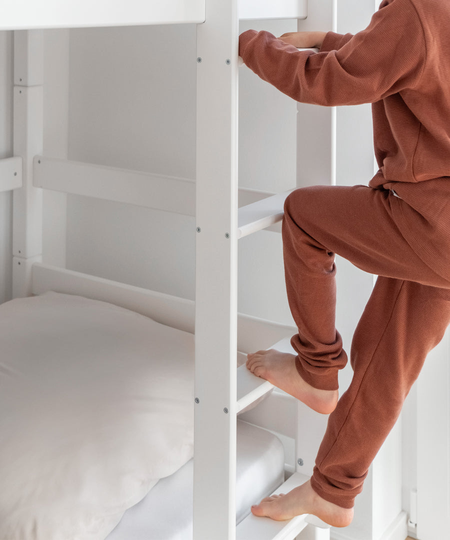 Trittsicher!*Dank unserer trittsicheren Leiter ist ein leichter und sicherer Einstieg für dein Kind garantiert.|Detailansicht der Leiter, auf der gerade ein Kind hoch steigt.
