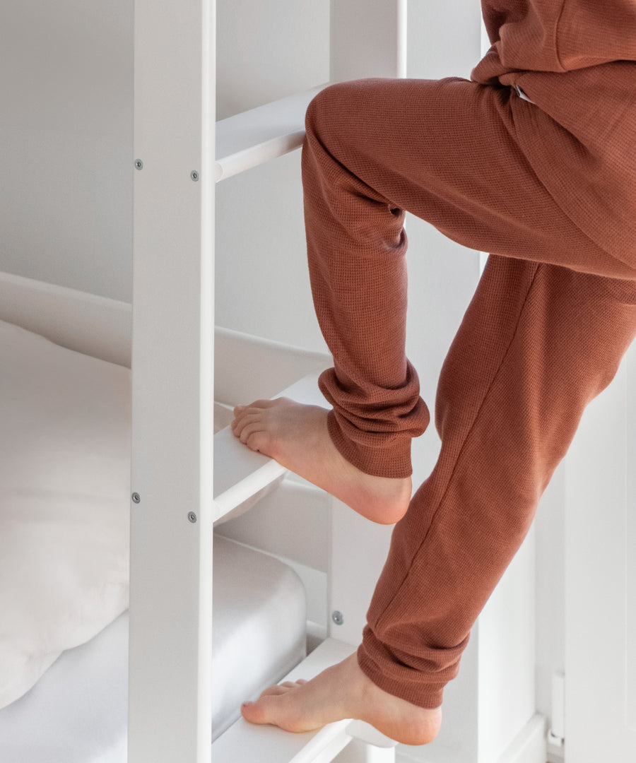 Trittsicher!*Dank unserer trittsicheren Leiter ist ein leichter und sicherer Einstieg für dein Kind garantiert.|Detailansicht der Leiter, auf der gerade ein Kind hoch steigt.