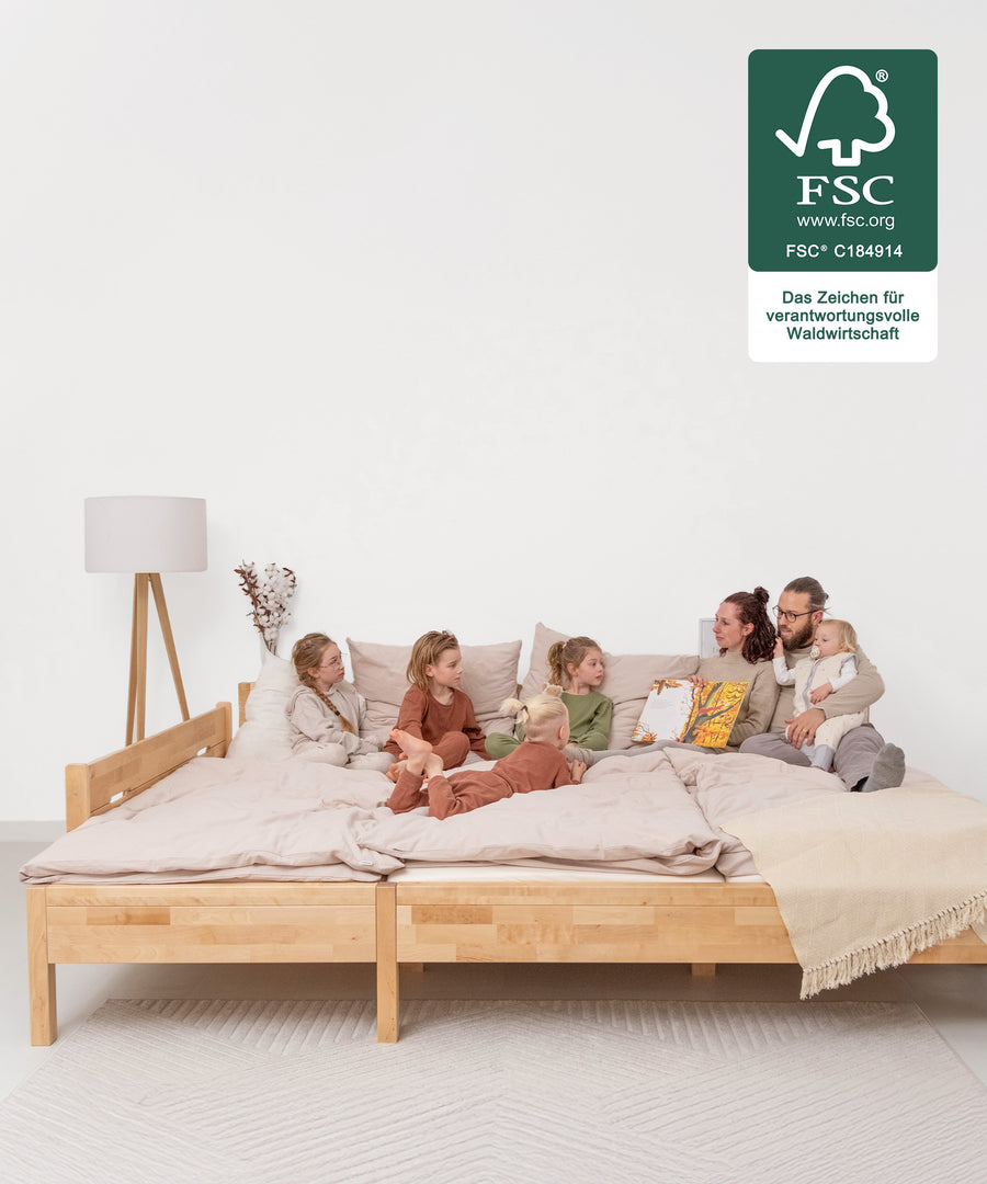 Platz für die ganze Familie*Das Familienbett bietet eine durchgehende, großzügige Liegefläche. So wird Co-Sleeping komfortabel und erholsam.|Familie auf Familienbett, Bett ist FSC zertifiziert.