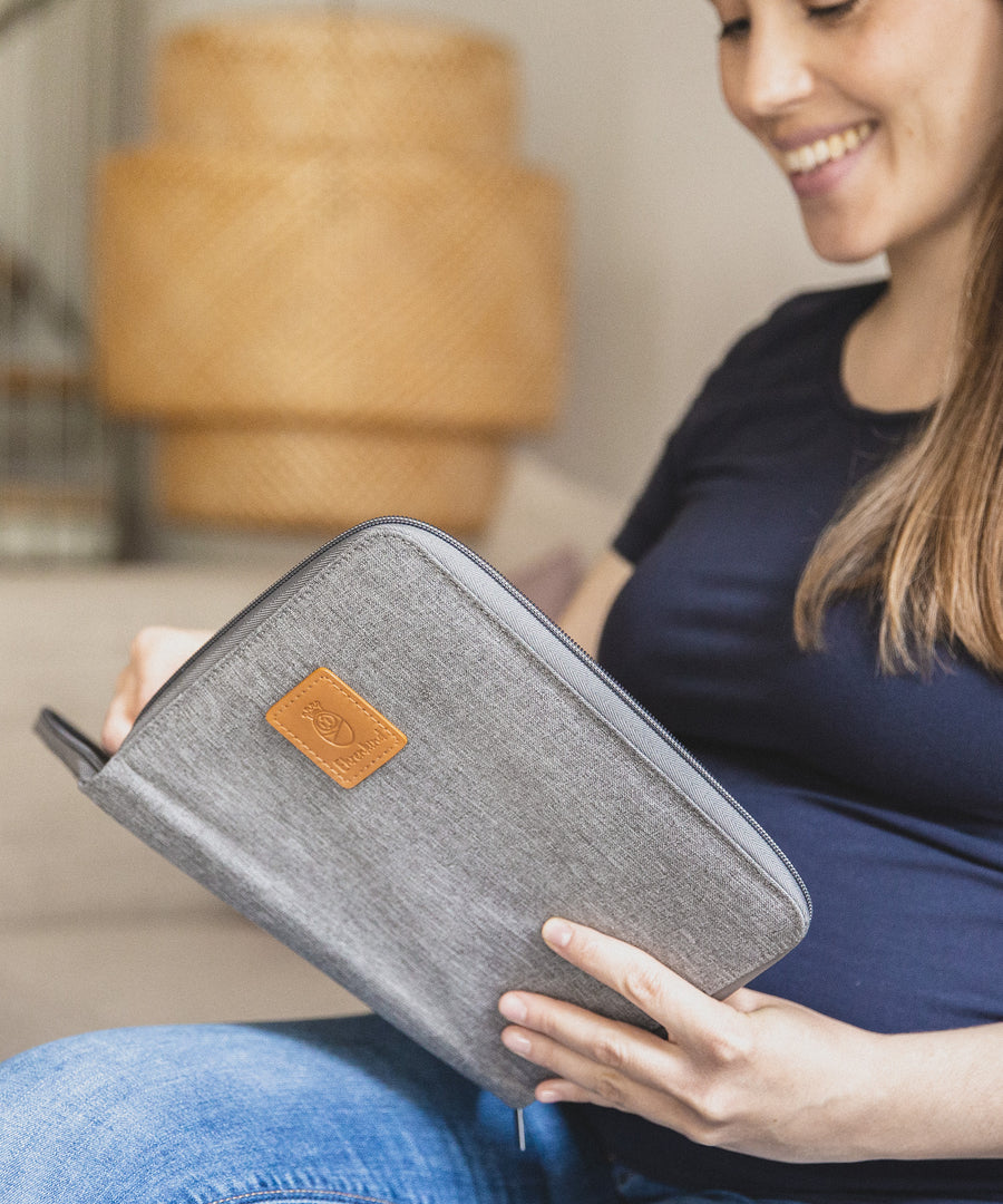 Hochwertiges & edles Design*Die kompakte Mutterpasshülle lässt sich gut in der Hand- oder Wickeltasche verstauen und schützt alle wichtigen Dokumente.|Schwangere Frau schaut in ihre geöffnete Mutterpasshülle.