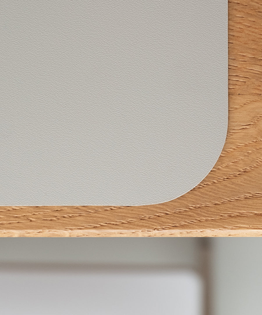 Robust & rutschfest*Das strapazierfähige Material mit rutschhemmender Unterseite ist robust und kratzfest - es hält den Familienalltag bestens aus. Tischset in Hellgrau.|Nahaufnahme der rutschfesten und robusten Oberfläche eines Tischsets auf Holz.