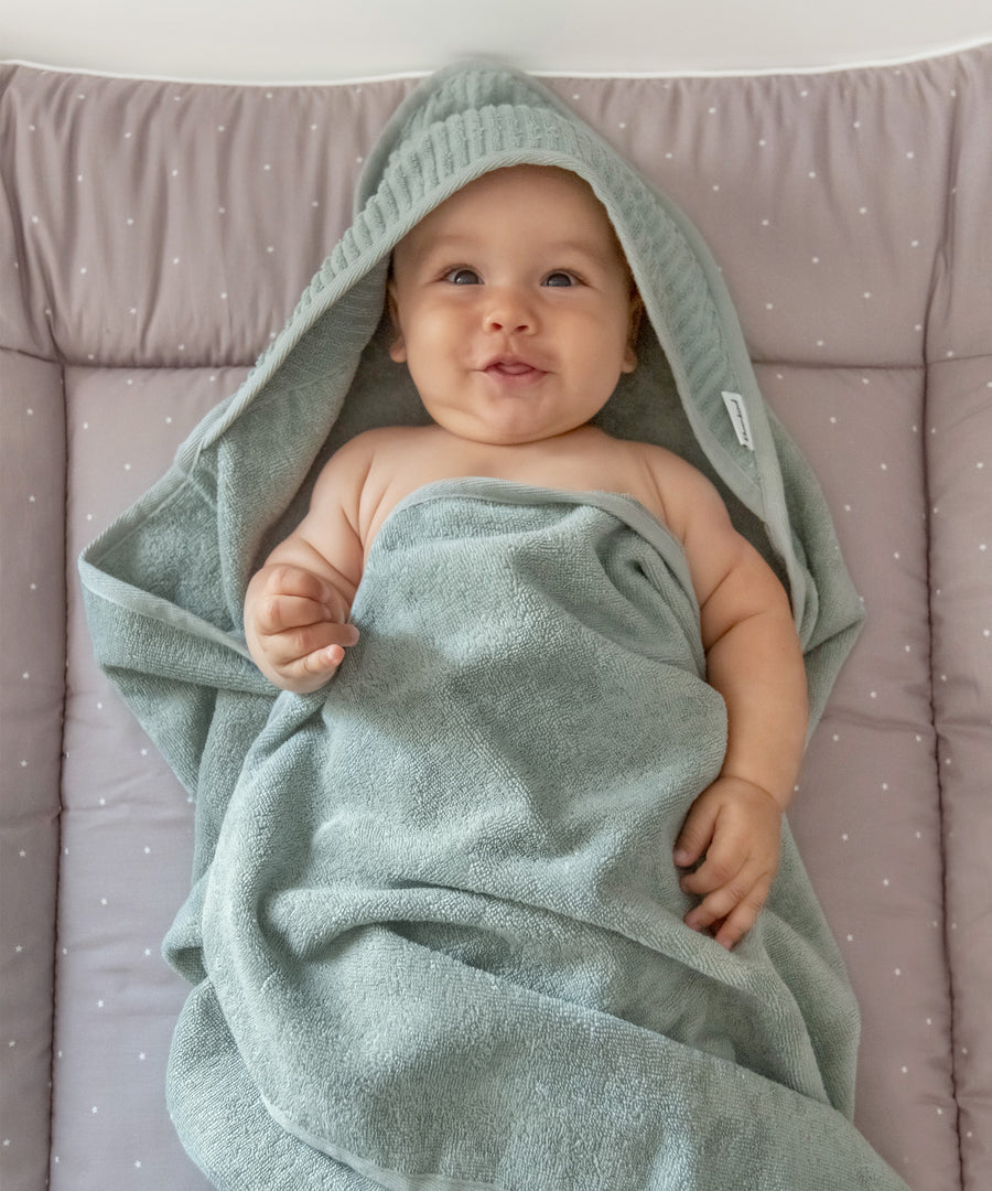 Baby ist in ein weiches Kapuzenhandtuch aus Bio-Baumwolle eingewickelt.