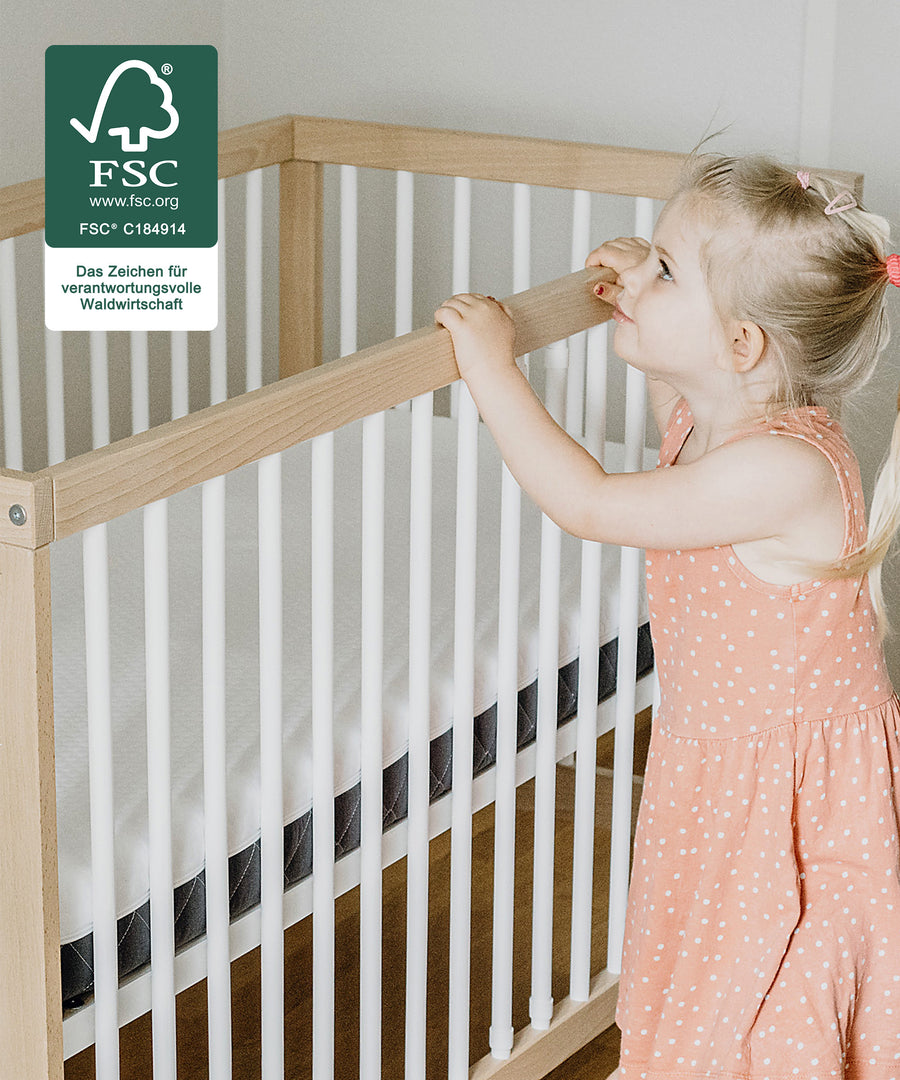 Robust & Kindgerecht*Das Bett bietet deinem Kind Geborgenheit beim
Spielen und Schlafen.|Kind steht im Babybett.