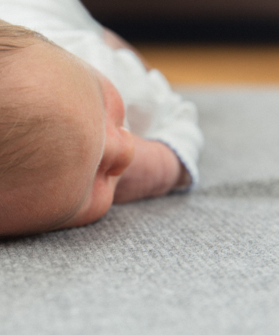 Neugeborenes Baby liegt auf Lammwoll-Babydecke.