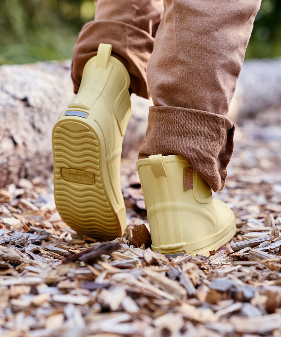 Natürliches Barfuß-Gefühl*Das leichte Barfuß-Design mit flexibler, durchgehend flacher Sohle und breitem Zehenbereich unterstützt die Fußentwicklung.|Kind trägt die Barfußgummistiefel in Vanille.