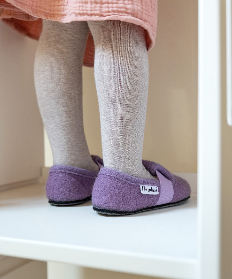 Mädchen mit Kinder-Hausschuhen steht auf Lernturm.