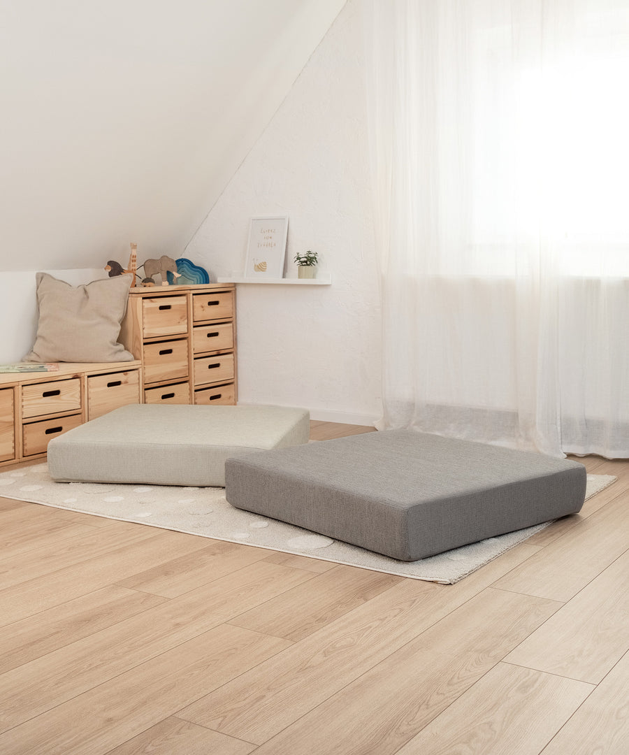 Quadratischer Hüpfspaß*Das 80 × 80 × 15 cm große Kissen eignet sich für Kinder ab ca. 12 Monaten und kann bis 40 kg Körpergewicht verwendet werden.| Hüpfpolster in Petrol und Natur liegen im Kinderzimmer.