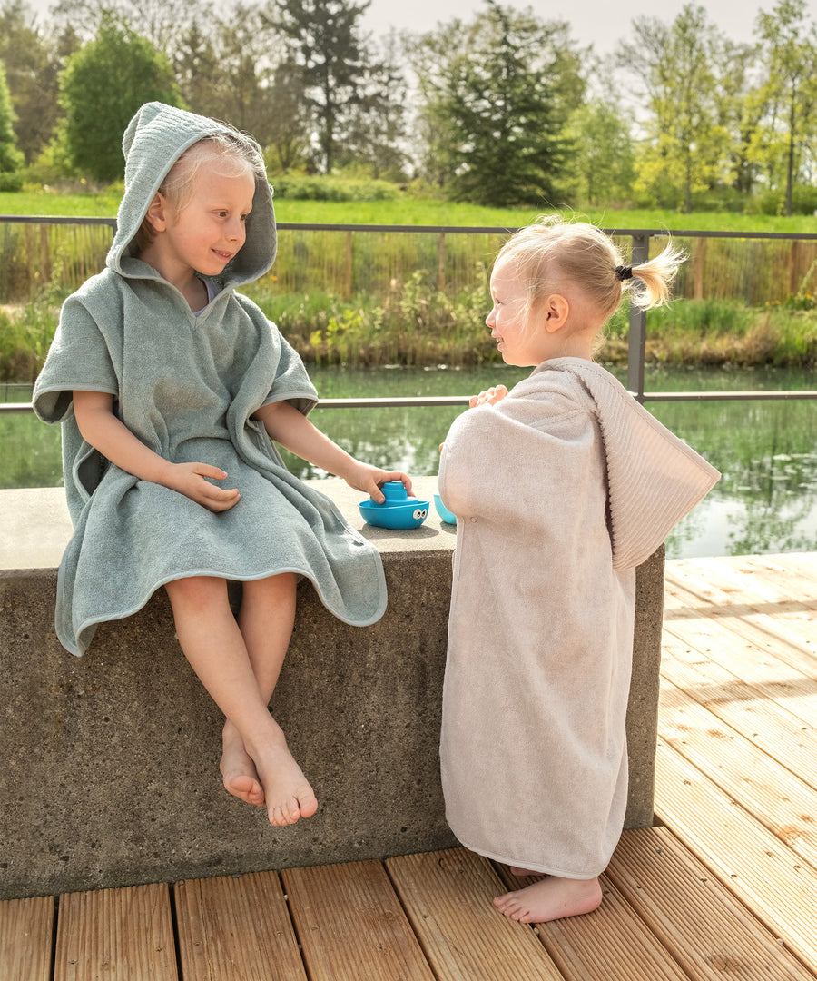 Kinder tragen den Badeponcho nach dem Schwimmen.