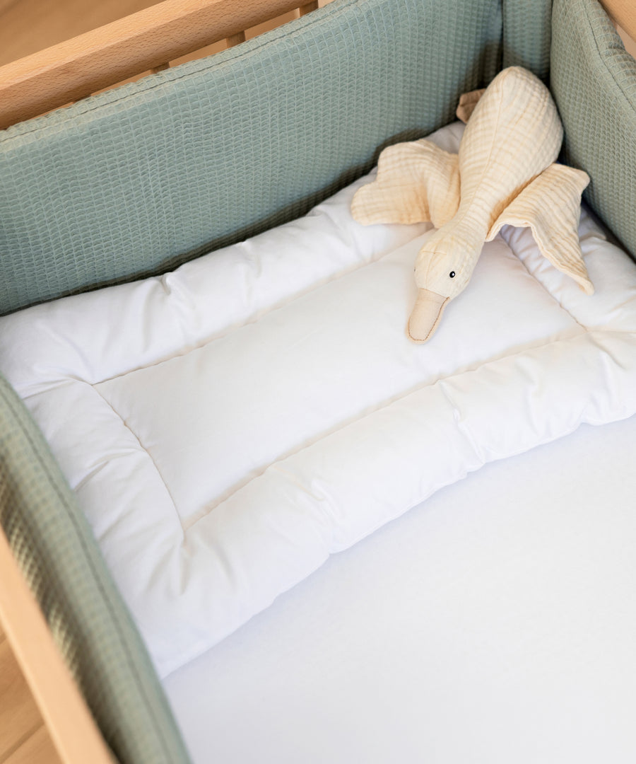 Kleinkindkissen mit Kuscheltier auf einem Kinderbett.