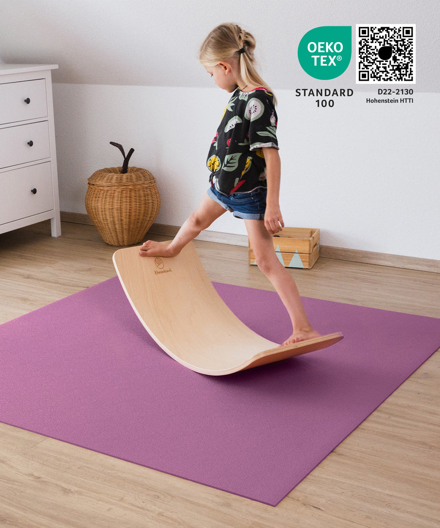 Dämpfend & isolierend*Die Krabbelmatte ist stoßdämpfend, wärmeisolierend und auch für Böden mit Fußbodenheizung geeignet. Krabbelmatte in Pflaume.|Kind balanciert mit BalanceBoard auf Krabbelmatte.