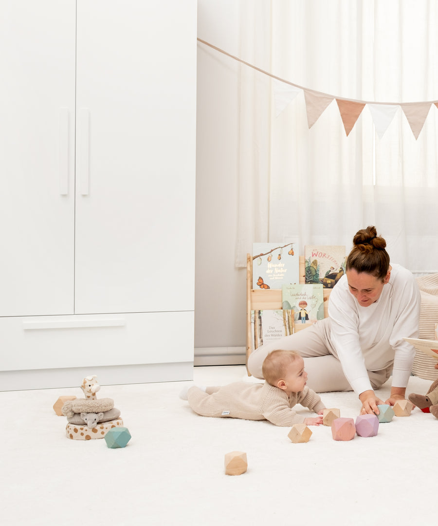 Familienmoment mit spielendem Kind vor dem weißen Linia Schrank.