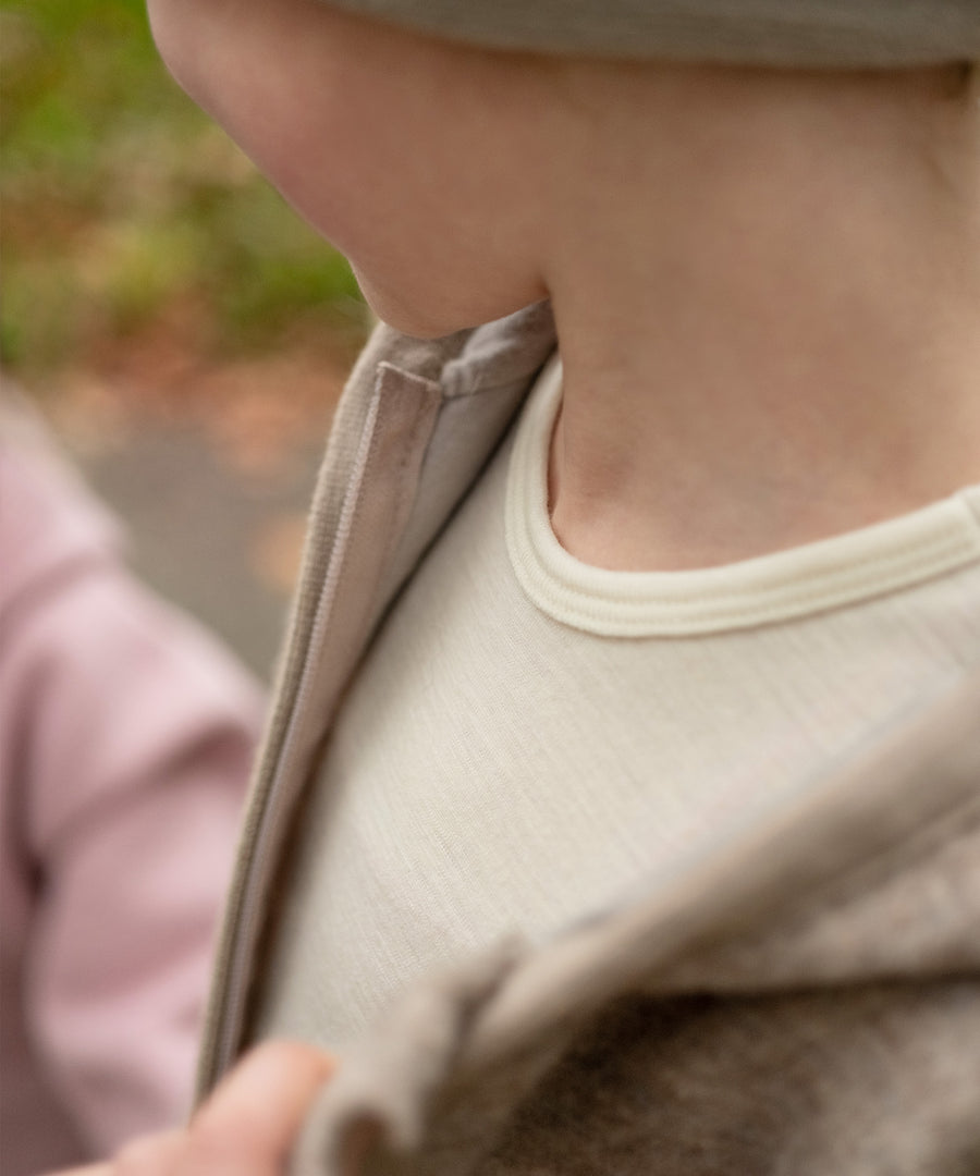Kind trägt Merino Oberteil natur unter Wollfleece Jacke.
