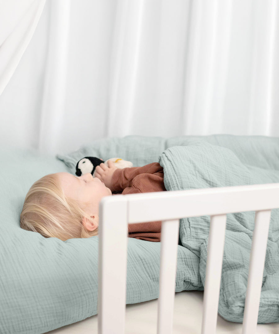 Für mehr Sicherheit*Das Bettgitter schützt dein Kind zuverlässig vor dem Herausfallen aus dem Bett und sorgt für extra Sicherheit.|Kind schläft in Bett mit Rausfallschutz.
