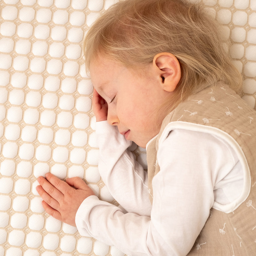 Schlafendes Kind in Musselin-Sommerschlafsack in Beige.