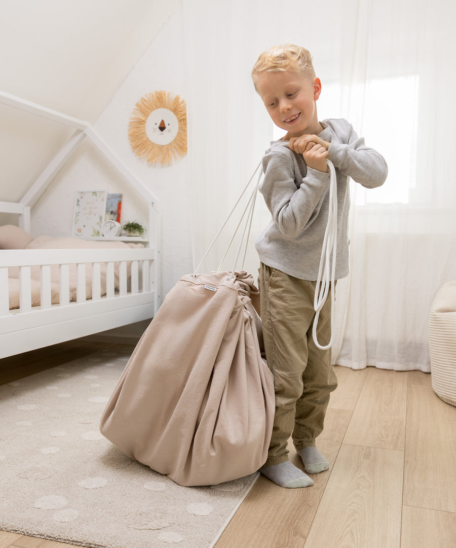 2in1: Spieldecke & Aufbewahrung*So geht Aufräumen ganz kinderleicht: Einfach Kordel ziehen und schon wird aus der Spieldecke ein geräumiger Spielzeugsack.| Kind trägt den Spielzeugsack.