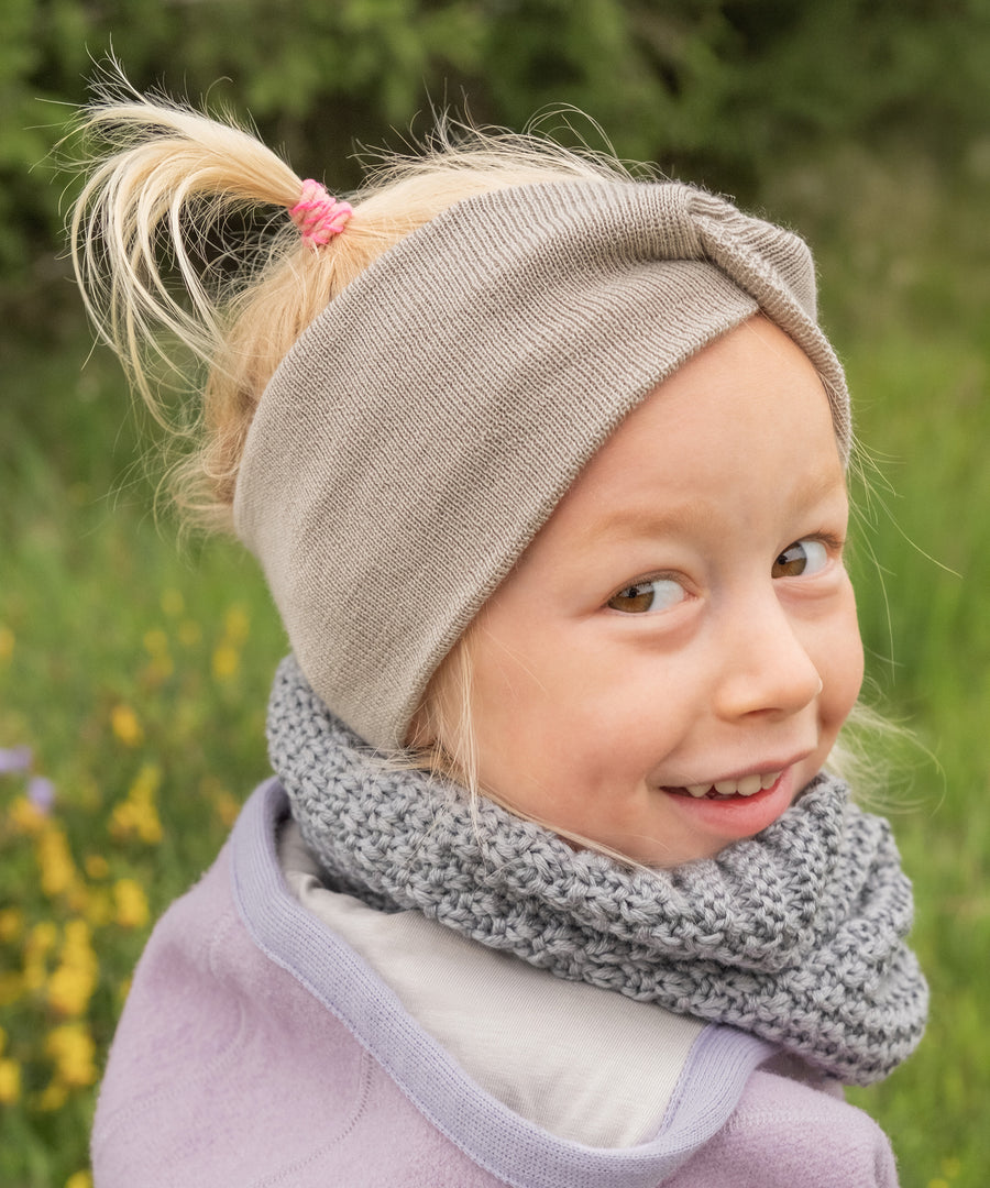 100 % Merino-Schurwolle*Weich, atmungsaktiv und temperaturregulierend – perfekt für empfindliche Kinderhaut auch bei täglichem Tragen.|Mädchen trägt das Stirnband in Beige.