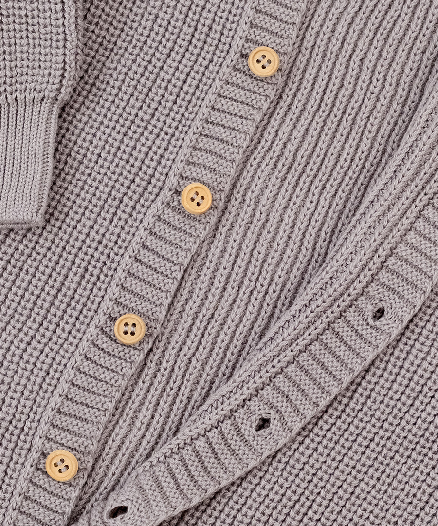 Ohne störende Nähte*Raglanärmel, durchgehende Knopfleiste und elastische Bündchen erleichtern das Anziehen und sorgen für einen perfekten Sitz.| Nahaufnahme Strickoverall Knopfleiste.