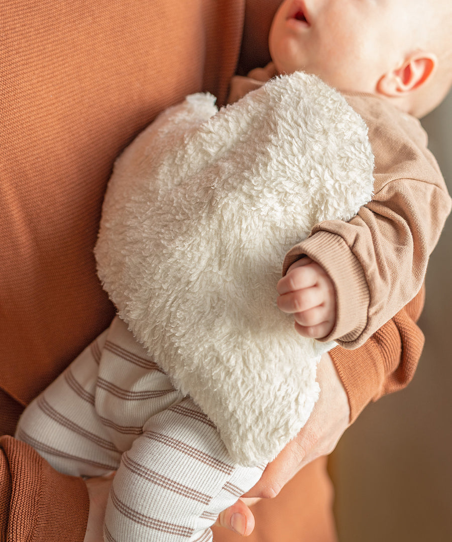 Wohltuende Wärme*Das Kirschkernkissen in Wolkenform spendet angenehme Wärme und sorgt für wohltuende Kuschelmomente bei Babys und Kindern.| Wärmekissen liegt auf dem Baby.