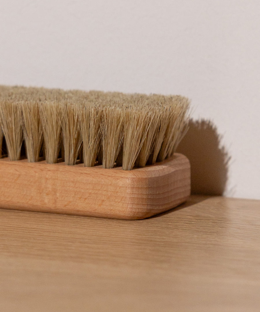 FSC®-zertifiziertes Holz*Der Griff aus geöltem Buchenholz stammt aus FSC®-zertifizierter Forstwirtschaft und liegt angenehm in der Hand.|Nahaufnahme der Bürste liegend.